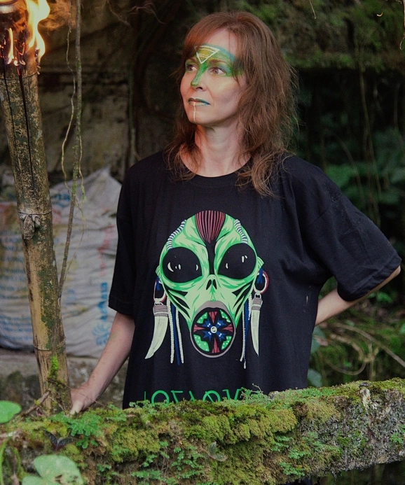 Woman wearing a Losaquis tribal alien t-shirt in a lush jungle setting, blending alien fashion with nature and ancestral aesthetics.